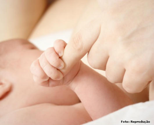 Amamentação: benefícios para a mamãe e para o bebê Bebê segurando o dedo da mamãe enquanto amamenta. Sensação de segurança e estreitamento emocional entre eles.