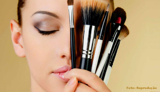 Mulher tentando se maquiar, mas em dúvida por causa dos inúmeros e diferentes tipos de pincéis