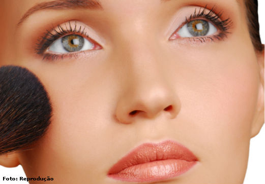 Modelo passando blush para retorcar a maquiagem com pincel grosso