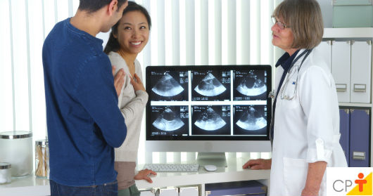 Especial Gravidez: 5ª semana de gestação - do 29º ao 35º dia pais conversando com a médica sobre a gravidez, visualizando em tela de computador os resultados da ultrassonografia