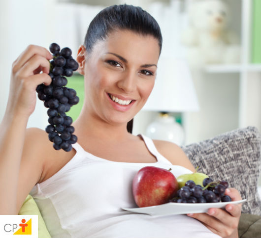 Especial Gravidez: 7ª Semana de Gestação - do 43º ao 49º dia gestante mostrando o tamanho de seu bebê exibindo um cacho de uvas